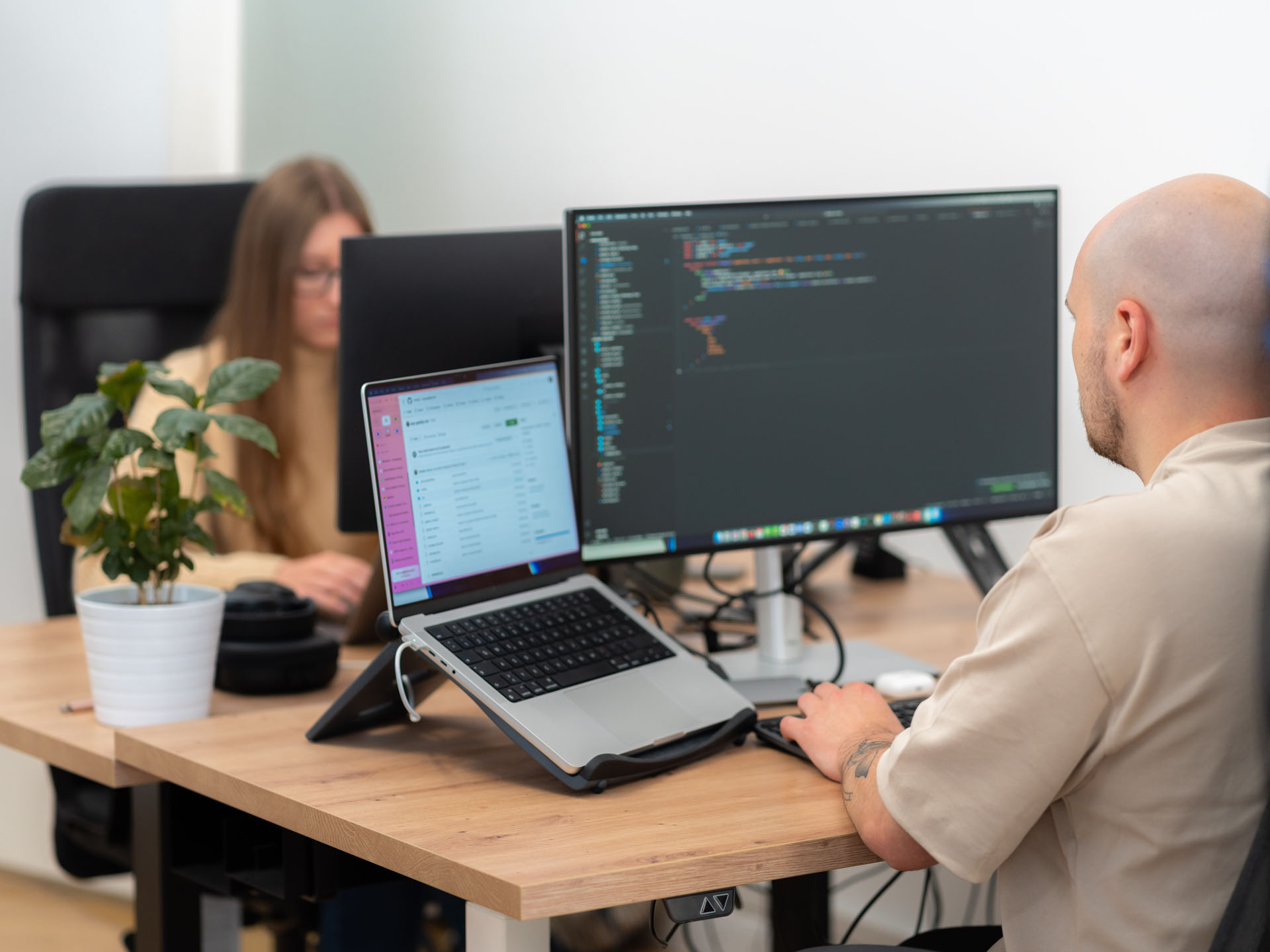 Zwei Programmierer sitzen auf ihrem Platz und arbeiten am PC.