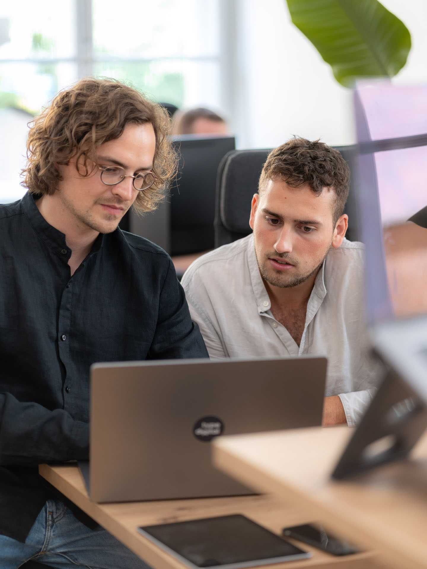 A designer and a developer are sitting in front of a laptop.